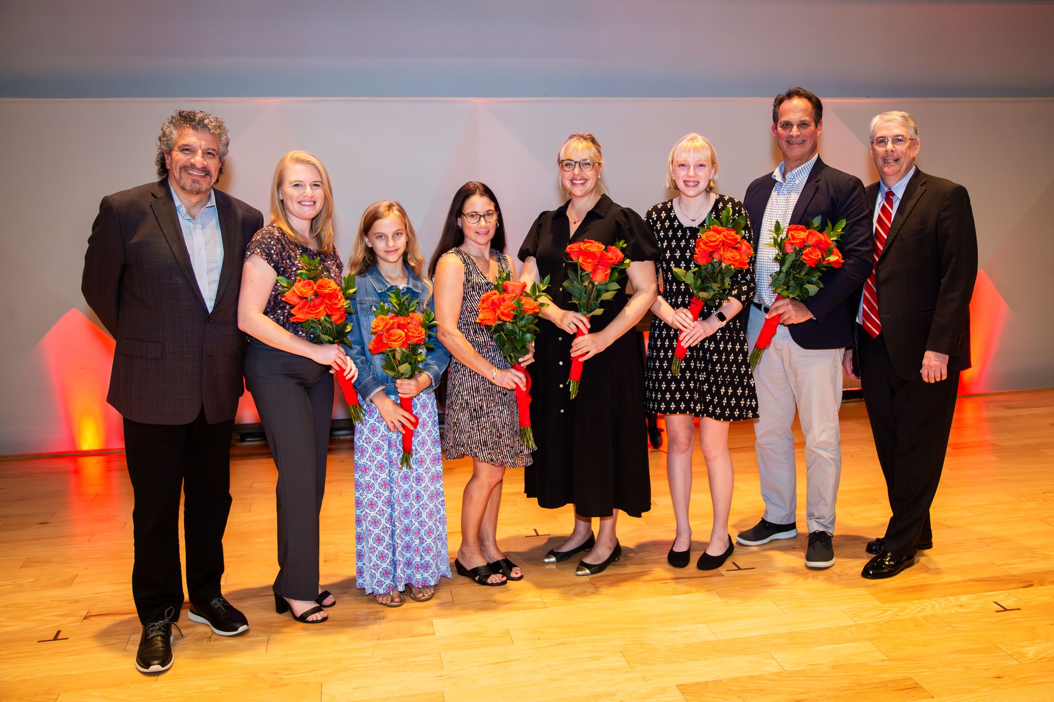 Representatives from Sarasota Orchestra's musicians, staff, education programs, and the Sarasota community standing on a stage holding red flowes